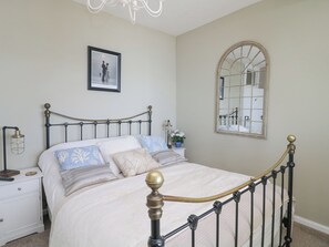 Un dormitorio con una cama, una mesita de noche, una lámpara, un espejo y un cuadro en la pared.