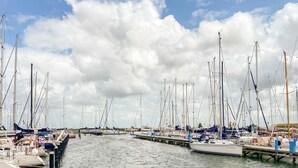 Un puerto deportivo con varios veleros amarrados, unidos por muelles, y un cielo nublado.