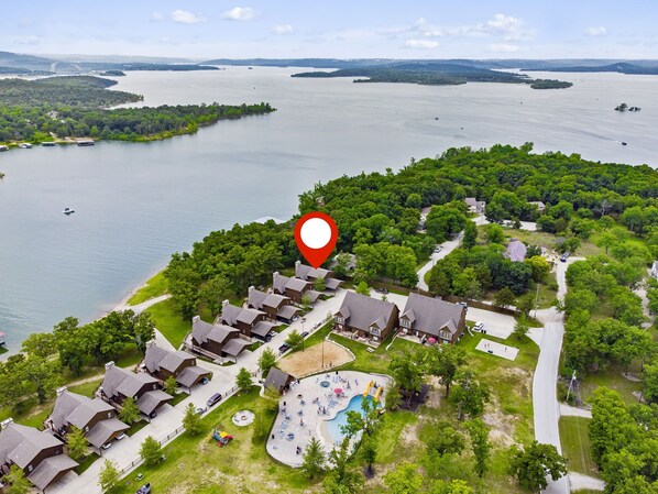 Een vakantiepark aan het meer met meerdere bungalowachtige huisjes, een zwembad en een steiger voor boten.