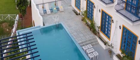 A rooftop pool with a clear view of the surrounding buildings, including a hotel with blue and white exterior and balconies.