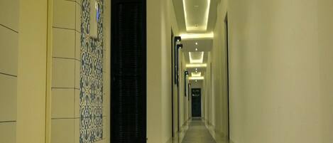 Un pasillo de hotel con baldosas estampadas, alfombra azul y una puerta negra.