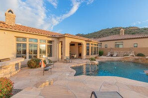 A modern house with a swimming pool, patio furniture, and a stone pathway.