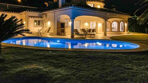 Ein großes, helles Haus mit Swimmingpool, mehreren Liegestühlen und einer Terrassenanlage.