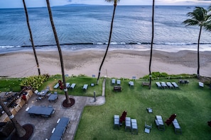 Un área de estar al aire libre con mesas y sillas, con vista a una playa y al océano.
