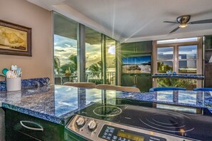 Una cocina con una isla cubierta de vidrio, electrodomésticos de acero inoxidable y vistas al exterior.