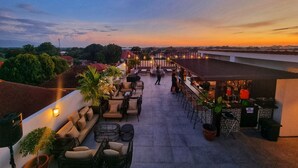 A rooftop terrace with outdoor seating, a bar area, and a view of the cityscape at sunset. - La Casa Blanca de Vigan Hotel (Vigan)