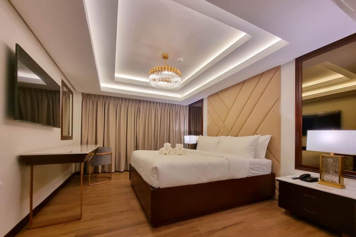 Une chambre d’hôtel moderne, dotée d’un grand lit, d’un bureau, d’une chaise, d’un miroir et d’un lustre.