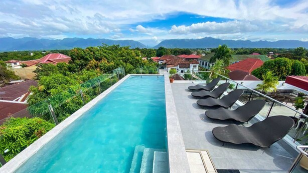 A rooftop pool with clear blue water, surrounded by lounge chairs and a view of mountains in the distance. - La Casa Blanca de Vigan Hotel (Vigan)