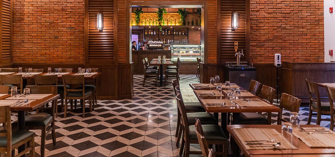 A restaurant with brick walls, a checkered floor, and wooden tables and chairs.