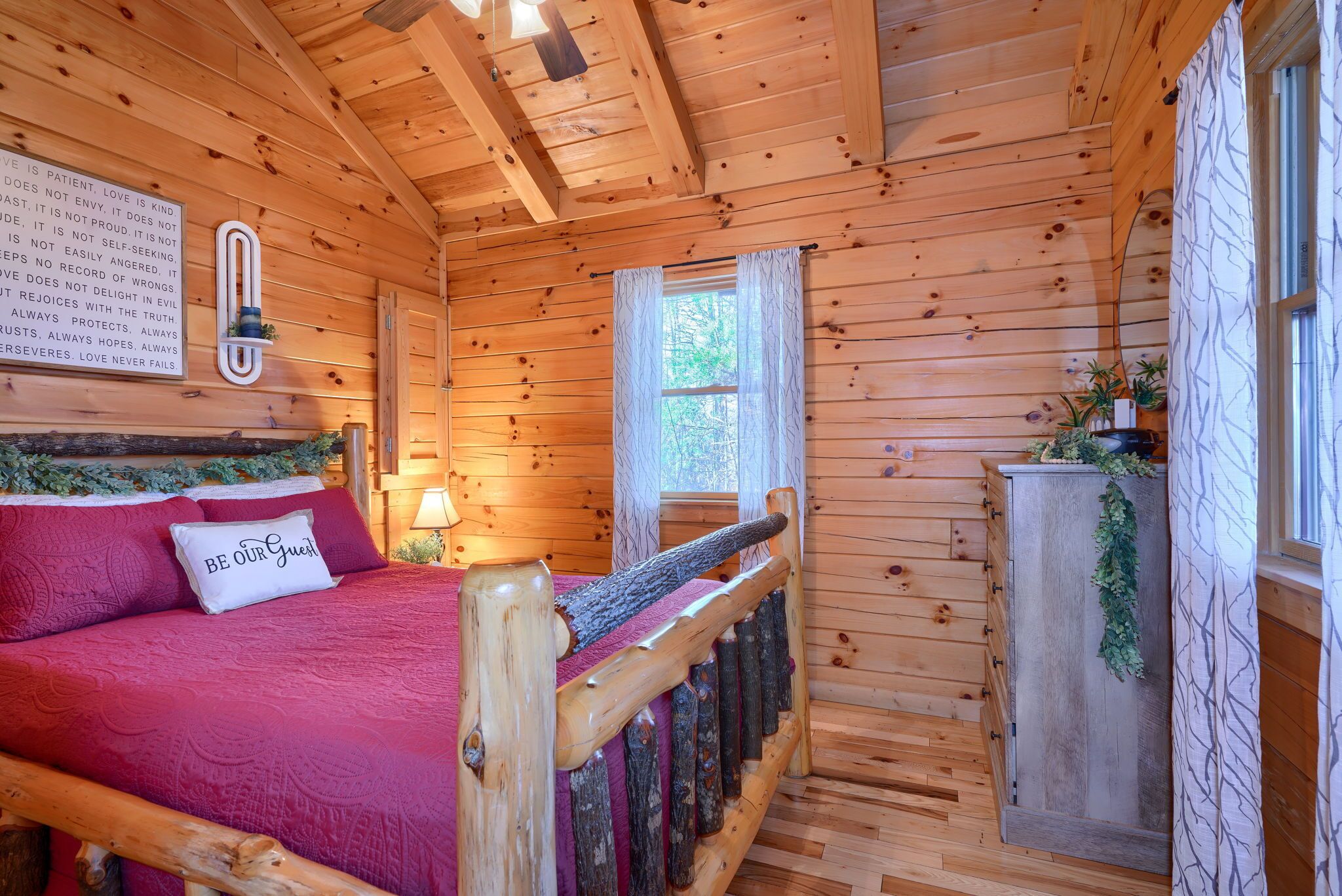 Una habitación de cabaña de madera con una cama, un ventanal y una pared con una cita inspiradora.