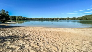 A sandy beach with calm water, trees, and a clear sky. - Awesome (sta)caravan in Hoogersmilde (Hoogersmilde)