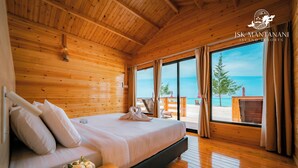 A wooden cabin room with a bed, a bench, and a view of the beach. - JSK Mantanani Island Resorts Trademark by Wyndham (Kampung Mantanani)