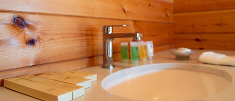 A wooden cabin interior with a bathroom sink, a faucet, and toiletries on the counter.