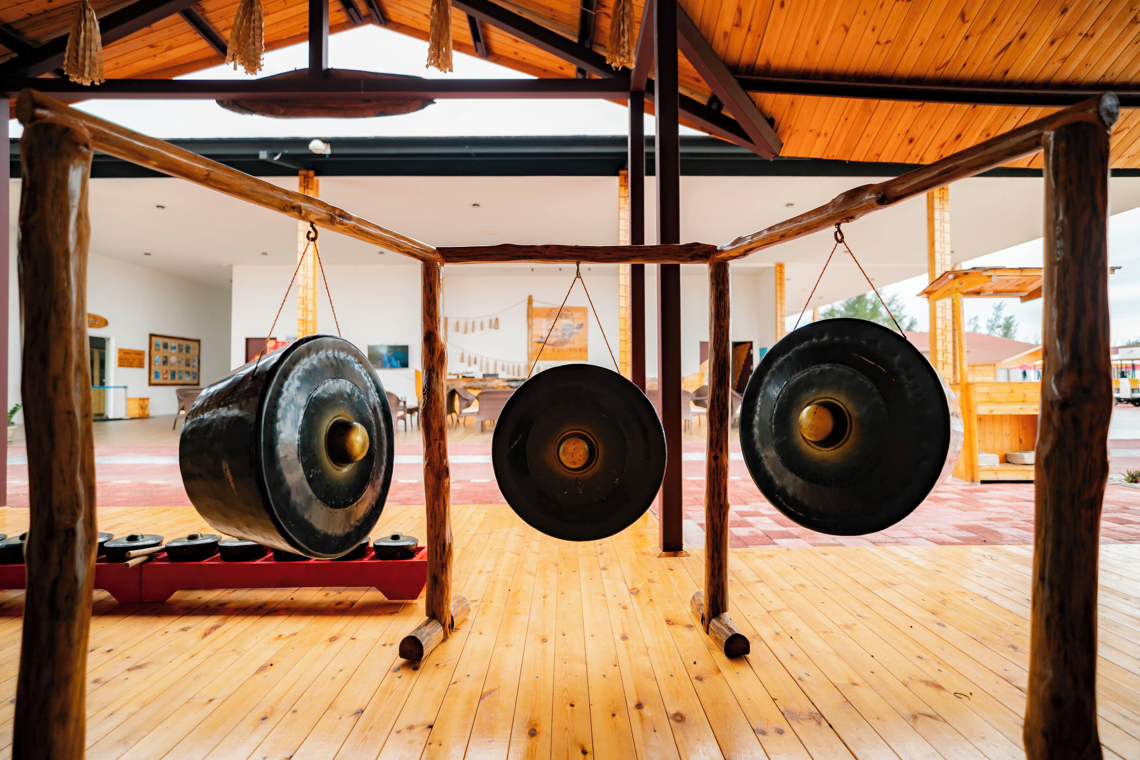 A wooden floor with hanging bells and a red bench.