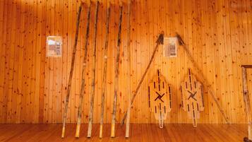 Ein Zimmer mit Holzwänden und Holzböden, mit einer hölzernen Wanduhr und mehreren Holzstücken, die an der Wand lehnen.