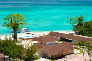 A beachfront hotel with multiple buildings, a swimming pool, and a dock with a boat. - JSK Mantanani Island Resorts Trademark by Wyndham (Kampung Mantanani)