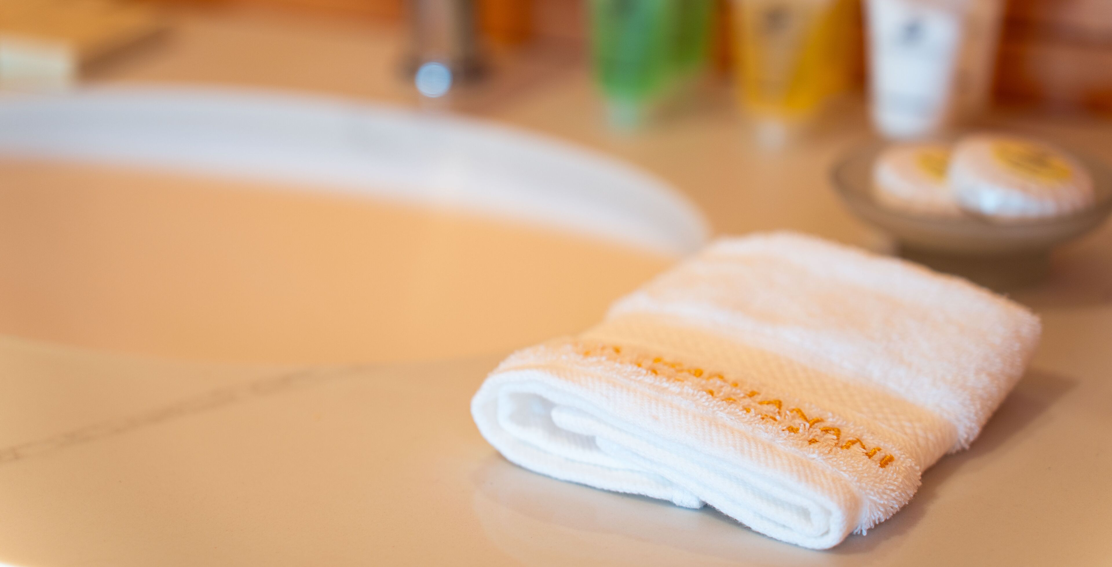 Una toalla blanca con costuras naranjas sobre una encimera de baño.