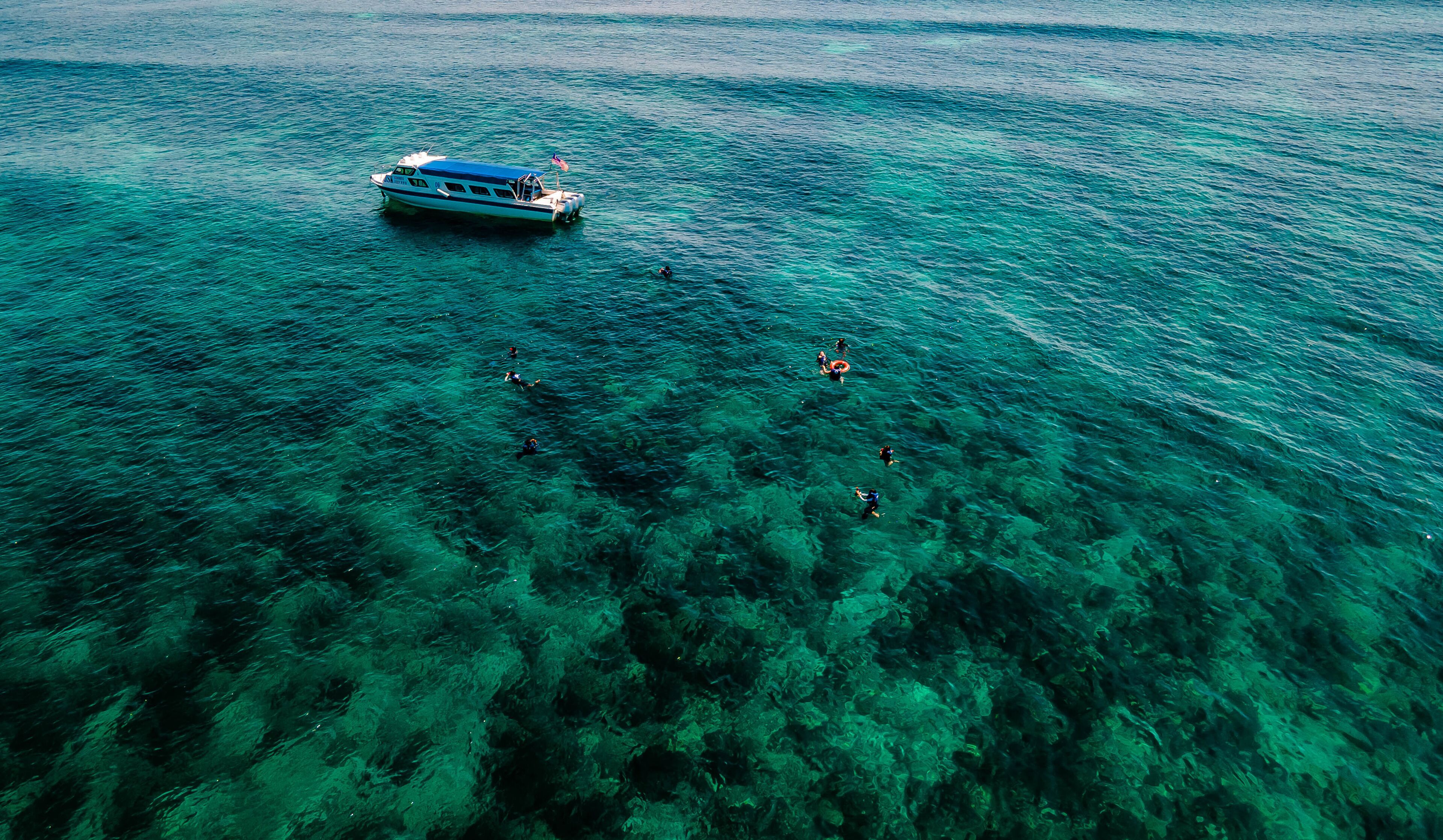 A boat with people swimming in the water.