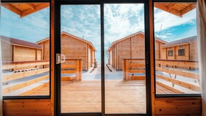 A wooden cabin with a central open door leading to a covered outdoor area with wooden benches. - JSK Mantanani Island Resorts Trademark by Wyndham (Kampung Mantanani)