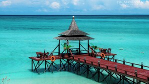 A wooden pier extending into turquoise waters with a thatched-roof structure at the end, featuring tables and chairs. - JSK Mantanani Island Resorts Trademark by Wyndham (Kampung Mantanani)