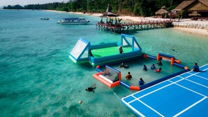 A beachside water park with inflatable play structures, a pier, and a beach area with umbrellas and lounge chairs. - JSK Mantanani Island Resorts Trademark by Wyndham (Kampung Mantanani)