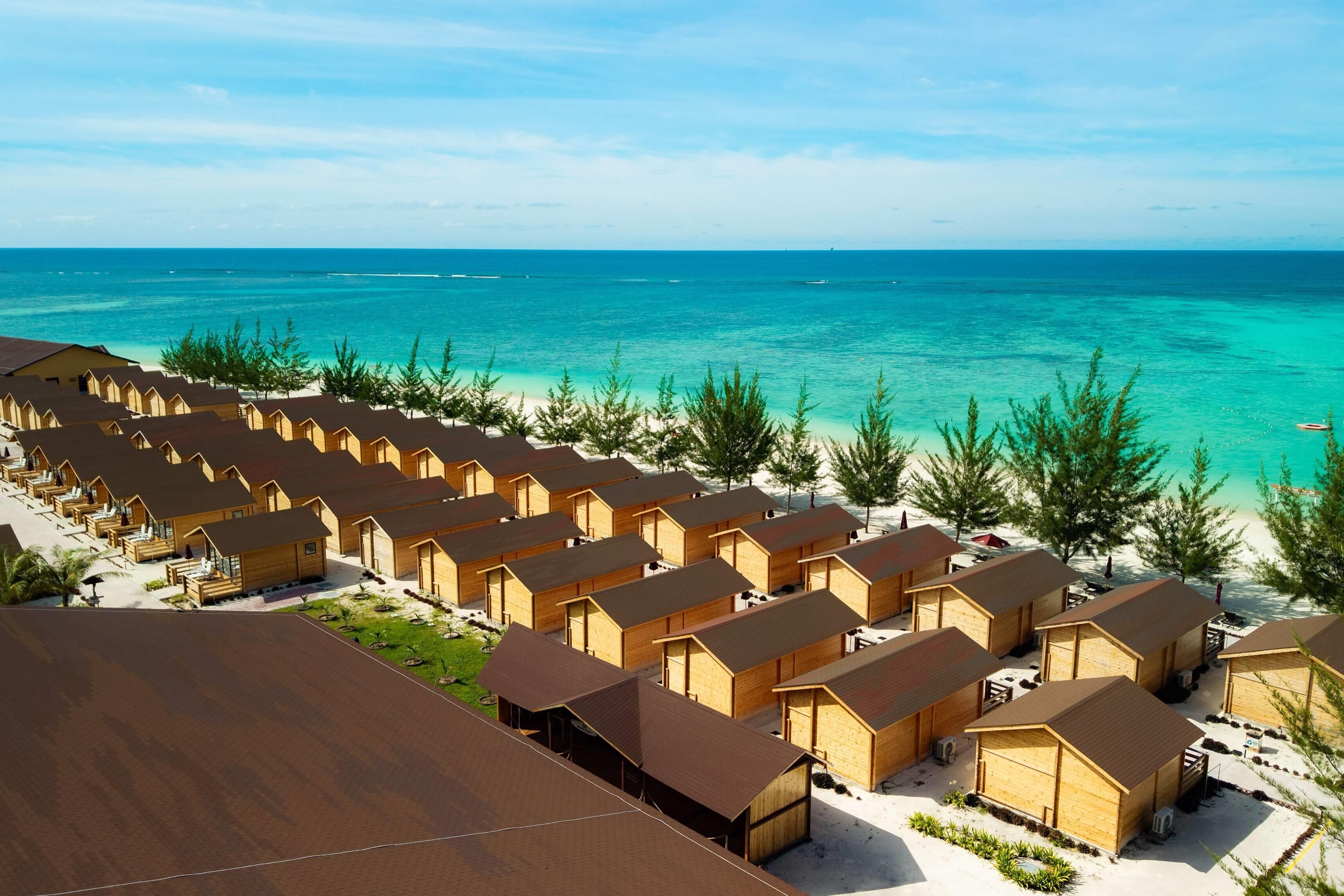 A row of wooden beach huts with a view of the ocean.