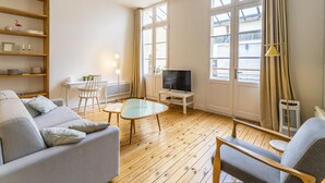 A living room with a sofa, a coffee table, a TV, and a desk with a lamp. - Superb apartment with Terrasse (Bordeaux)