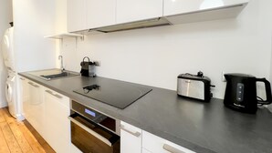 A modern kitchen with a black countertop, stainless steel appliances, and white cabinetry. - Superb apartment with Terrasse (Bordeaux)