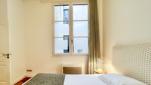 A hotel room with a bed, a window, a radiator, and a lamp. - Superb apartment with Terrasse (Bordeaux)