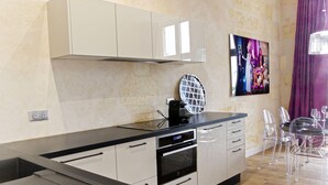 A modern kitchen with a black countertop, stainless steel appliances, and a dining area with clear chairs and a glass table.