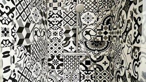 A bathroom with a tiled wall featuring intricate black and white patterns.