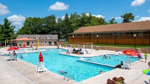 A swimming pool area with multiple pools, lounge chairs, and umbrellas.