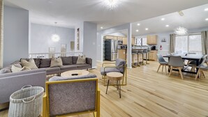 A spacious living area with a grey sofa, a round coffee table, and a dining table with chairs.