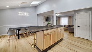 A modern kitchen with a wooden island, grey walls, and a dining area with chairs.