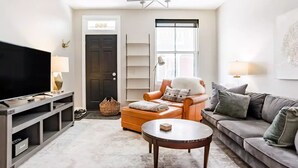 Un salon avec un téléviseur, un canapé, un fauteuil et une table basse.