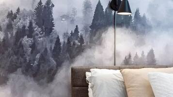 A bedroom with a bed, a nightstand, a lamp, and a wall mural of a forest.