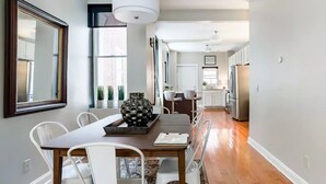 Un espace repas moderne avec une table en bois, des chaises blanches et un vase décoratif.