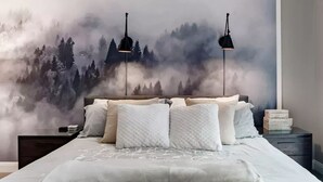 Une chambre à coucher avec un lit, deux lampes de chevet, une table de chevet et une fresque murale représentant une forêt.