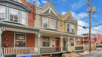 A row of Victorian-style townhouses with bay windows, a red door, and a white picket fence.