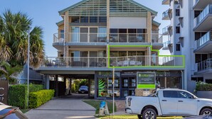 A two-story building with a green roof, balconies, and a sign for Cotton Tree Real Estate.