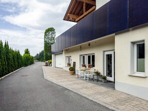 Een modern gebouw met een overdekt terras, een garage en een rij potplanten.