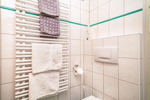 Een badkamer met een handdoekrek, een toiletrolhouder en een handdroger.