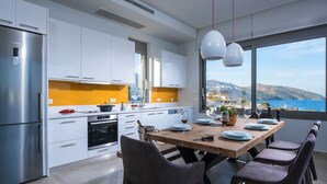 A modern kitchen with a large island, stainless steel appliances, and a view of the sea. - Luxurious Sea View Villa in Agios Nikolaos (Agios Nikolaos)