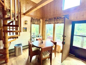 A wooden interior with a round table and chairs, a staircase, and a view through a glass door. - The Snow Shack 2BR w Hot Tub, Stream, Fireplace, Steam Rm on 5 Acres Near Breck (Alma)