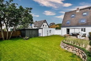 A residential property with a well-maintained lawn, a wooden fence, and a stone retaining wall.