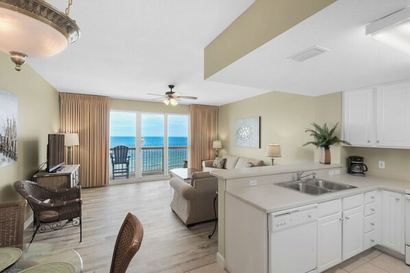 A modern hotel room with a balcony, a dining area, and a kitchenette.
