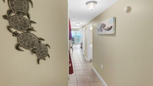 Ein Flur mit Wandkunst, die Schildkröten zeigt, einer Deckenleuchte und einer Tür zu einem Balkon mit Aussicht.