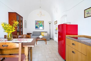 Un espacio habitable compacto con zona de comedor, un sofá, un refrigerador rojo y un armario de madera.