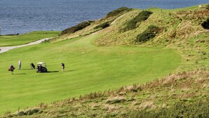 A golf course with a view of the sea, a path, and a few people. - Tir Eironwy (Pwllheli)