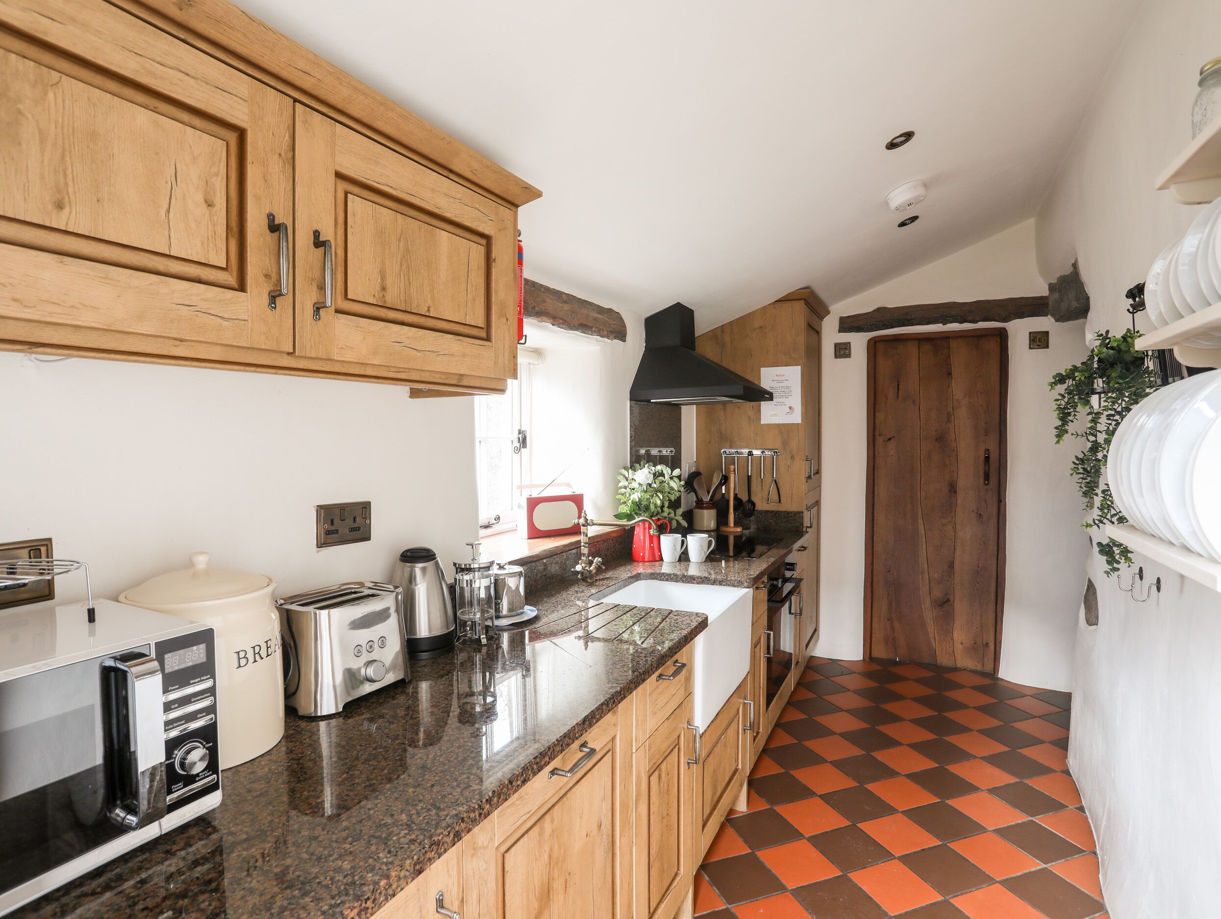 A kitchen with wooden cabinets, a granite countertop, a toaster, a kettle, and a sink.